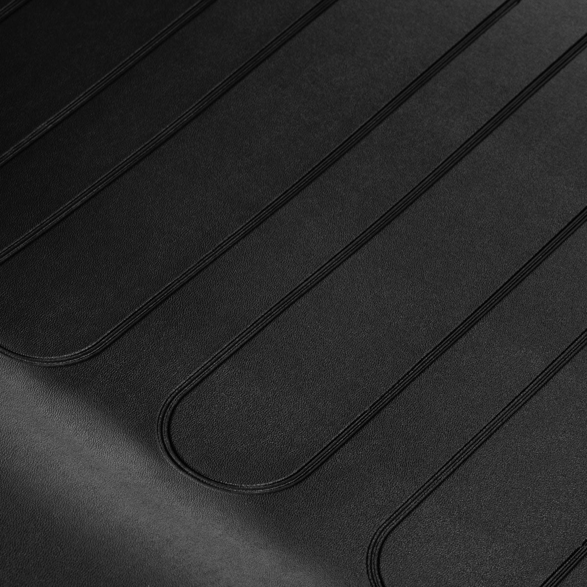 Close-up of black textured upholstery with raised curved seams.