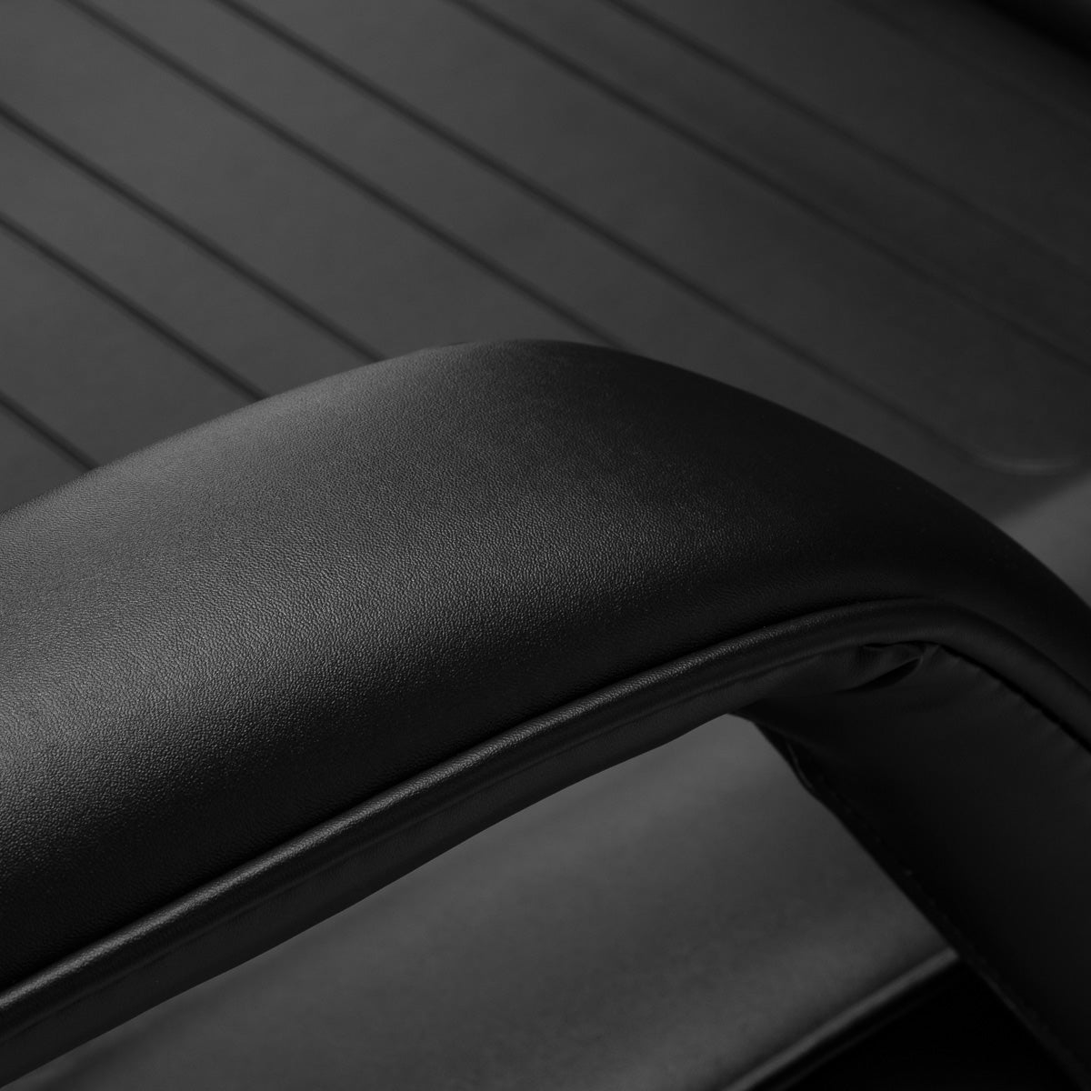 Close-up of a black leather armrest on a hydraulic treatment chair for salons.